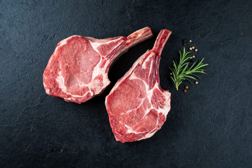 Raw dry aged bone-in back veal chops with pepper and herbs