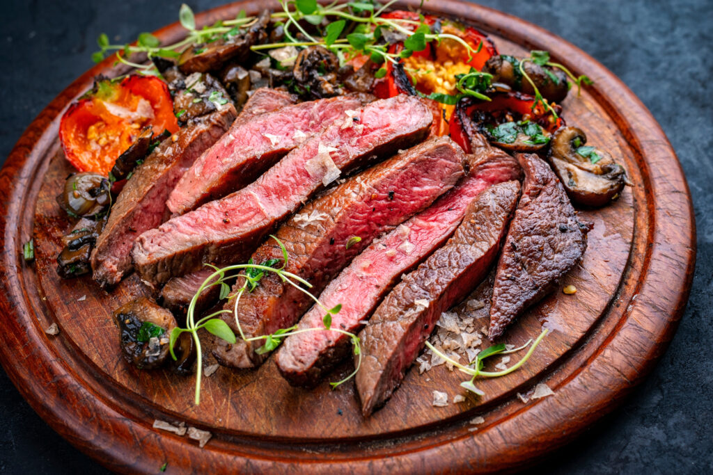 Traditional barbecue grass-fed dry aged roast beef steak tagliata with grilled mushrooms and vegetables cut on wooden board